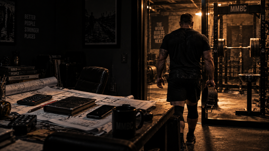 Architect walking from a dark planning office toward a warmly lit powerlifting gym, carrying a worn lifting belt, with architectural plans and a closed notebook left behind on the desk.