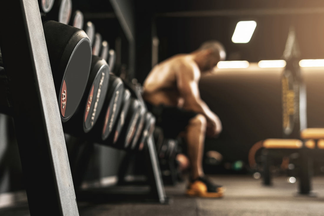 Exhausted athlete resting in a gym during training, showing the discipline and grind of long-term fitness progress.