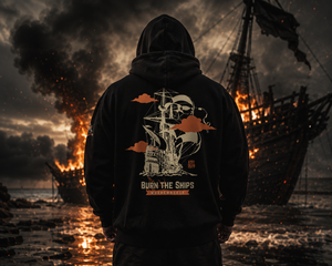 Black MooreMuscle Burn The Ships heavyweight hoodie photographed in front of a burning ship scene with dramatic smoke, fire, and cinematic atmosphere.