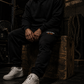 Burn The Ships heavyweight sweatpants styled in a rugged industrial environment, showcasing premium fleece construction and relaxed fit.