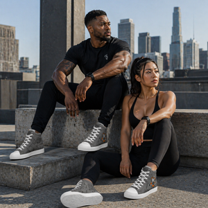 Asian female and African American male athletes wearing MooreMuscle grey high top sneakers with white soles, seated on a city rooftop in athletic apparel, showcasing a strong and athletic lifestyle in an urban setting