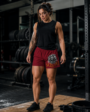 Male athlete walking away in MooreMuscle Squat Collection shorts carrying a weight plate