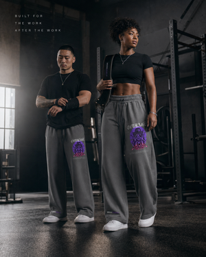 Black female athlete and Asian male lifter wearing MooreMuscle Courage sweatpants inside a warehouse strength gym.