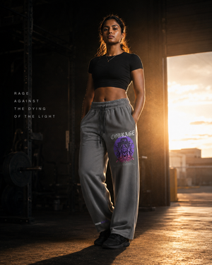South Asian female athlete wearing MooreMuscle Courage sweatpants in a dark warehouse gym at sunset.