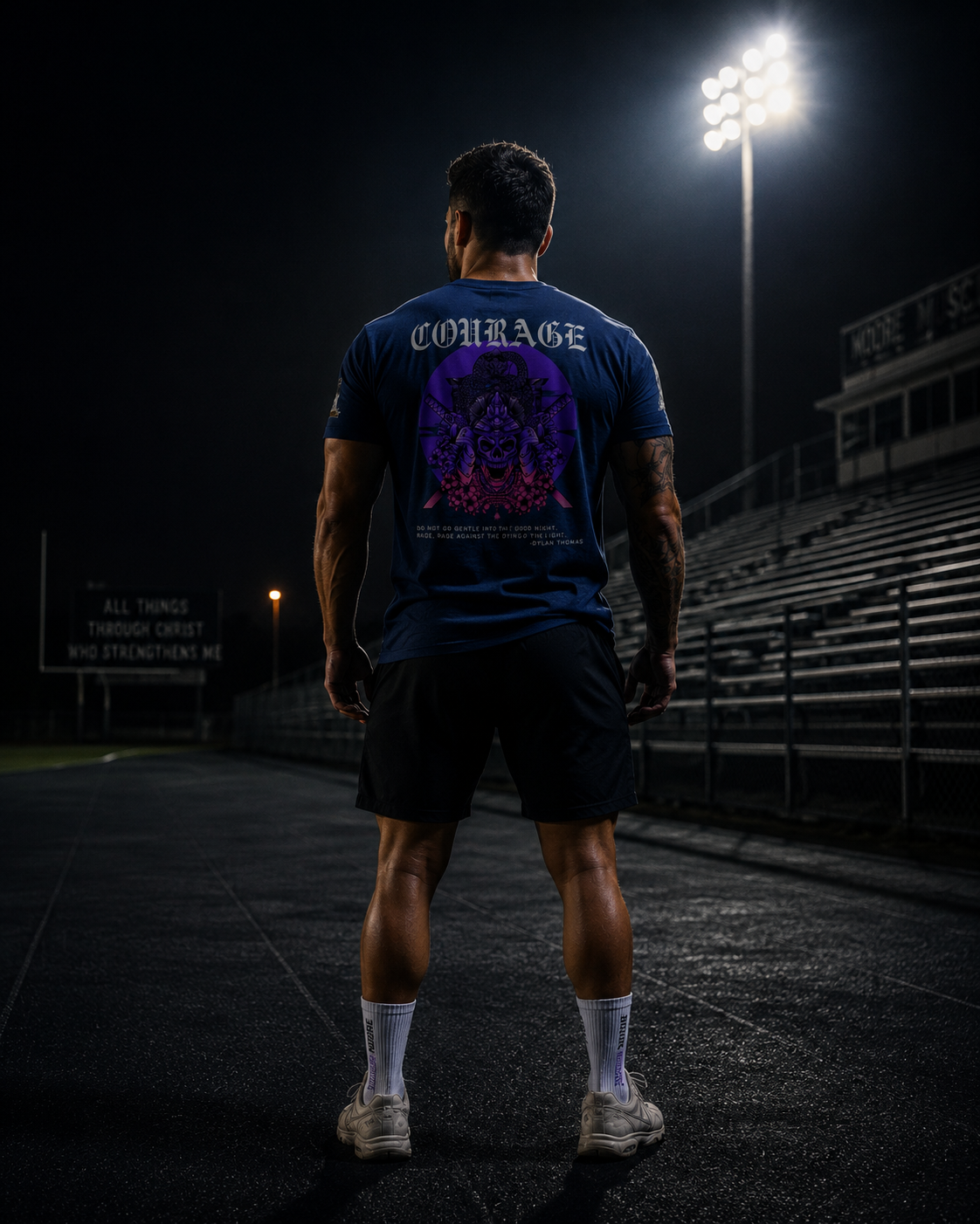 Athlete standing under stadium lights wearing the Courage Collection T-shirt with the samurai skull back graphic and Dylan Thomas quote.