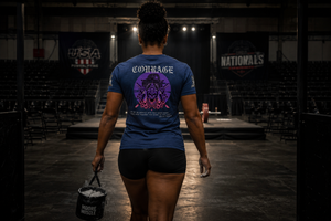 Person wearing a blue t-shirt with 'Courage' on the back, standing in an indoor arena.