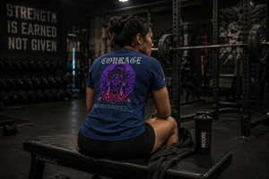 Athlete seated on a gym bench wearing the Courage Collection T-shirt before training in a powerlifting environment.