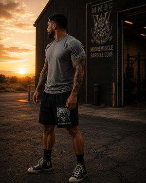 Athlete wearing MooreMuscle Five Rings training shorts outside MooreMuscle Barbell Club at sunset.