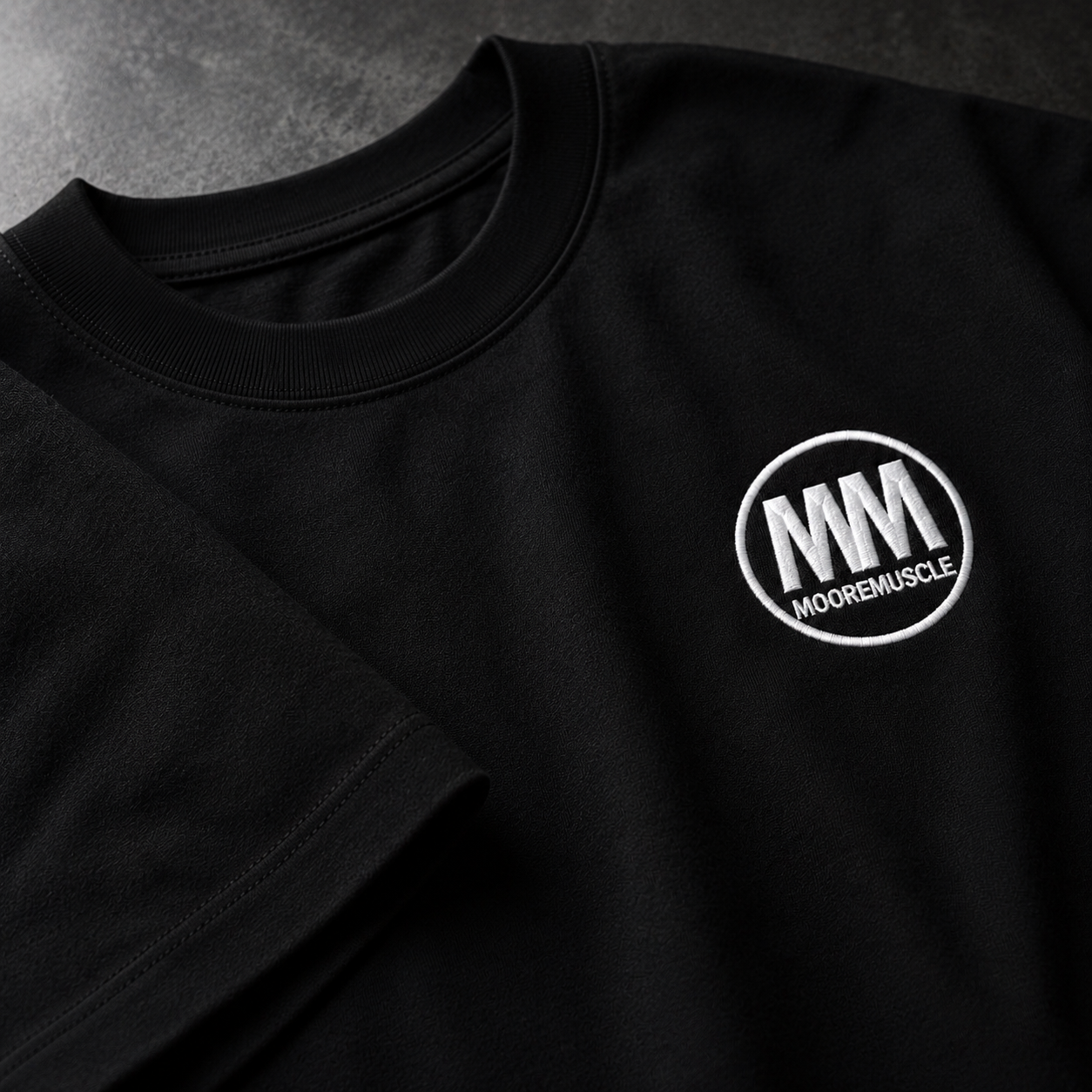 Black t-shirt with a white embroidered MM logo on a dark background