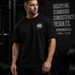 Athlete wearing a black MooreMuscle MM Heavyweight Tee inside a dark cinematic powerlifting gym with moody lighting, oversized fit styling, and strength culture atmosphere.