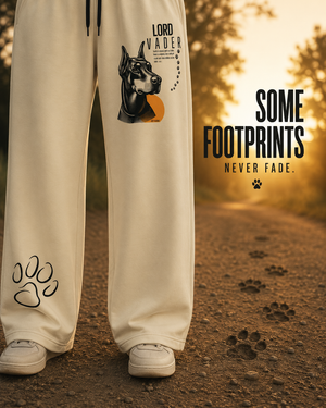 Close-up of Lord Vader wide-leg sweatpants showing front paw print graphic with dog footprints along a gravel path.