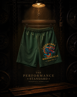 Green MooreMuscle Legendary performance shorts displayed under a warm spotlight inside a dark gym.