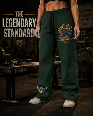 Female athlete wearing green MooreMuscle Legendary sweatpants next to a competition bench with the text The Legendary Standard.