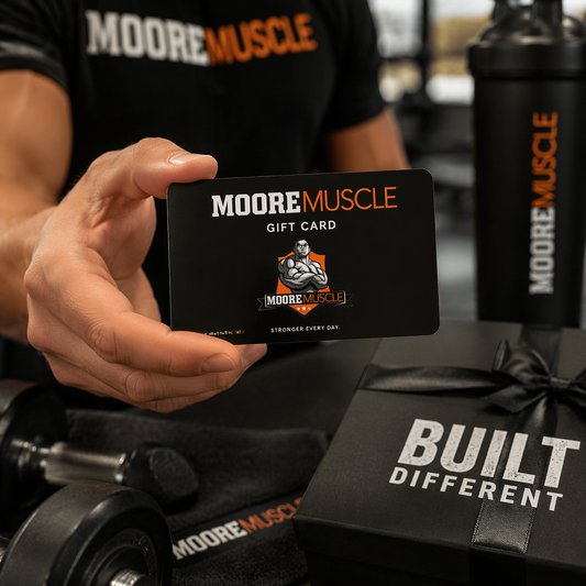 MooreMuscle gift card held in hand inside gym with fitness apparel and equipment background