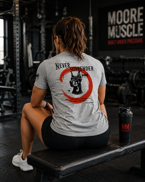 Female athlete seated on a gym bench wearing the Never Surrender athletic gray tee with Doberman back graphic.