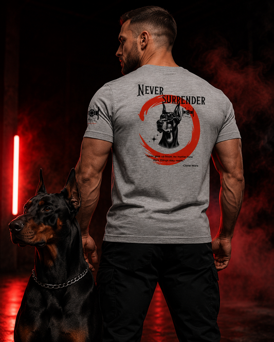Male athlete wearing the Never Surrender tri-blend tee with Doberman back graphic beside a black Doberman in red-lit gym setting.