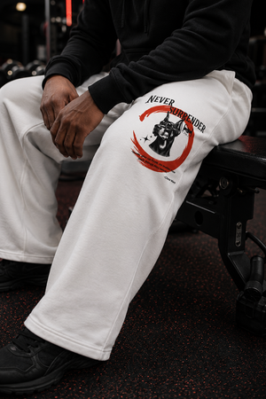 Person wearing white sweatpants with the Never Surrender design sitting on a bench.