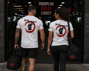 Male and female athletes walking into the gym wearing matching Never Surrender tees with Doberman back graphics.