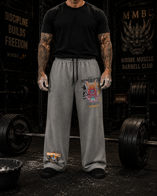 Athlete wearing MooreMuscle Warrior Collection wide-leg sweatpants in gray inside a powerlifting gym.