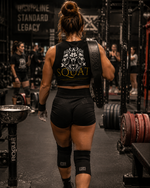 Female powerlifter walking through gym wearing MooreMuscle Squat crop top