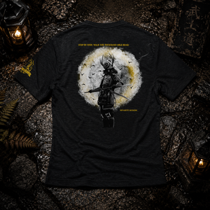MooreMuscle Thousand Mile Tri-Blend Tee laid flat on a wet stone surface with samurai back graphic, lantern lighting, and warrior-inspired Japanese aesthetic.