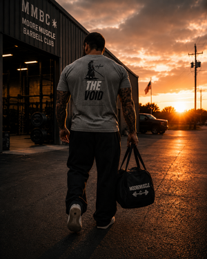 The Void tri-blend tee worn outside MooreMuscle Barbell Club at sunset.