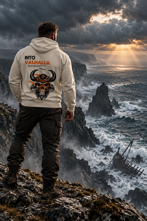 Man standing on sea cliffs at sunset wearing the Into Valhalla heavyweight fleece hoodie, back graphic view