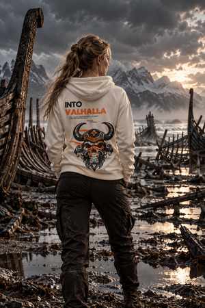 Woman in a ship graveyard wearing the Into Valhalla unisex hoodie, back view showing the Viking skull graphic
