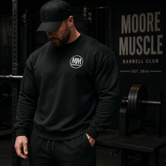 Athlete wearing a black MooreMuscle MM Heavyweight Crewneck Sweatshirt inside a dark premium powerlifting gym with cinematic lighting and strength culture atmosphere.