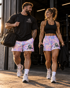 Male and female athletes walking out of a gym at golden hour wearing MooreMuscle Afterglow pastel tie-dye unisex training shorts