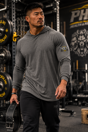 Close-up front view of a man wearing the MooreMuscle Squat Hooded Long-Sleeve Tee at Priority Health and Fitness, sleeve patch detail visible