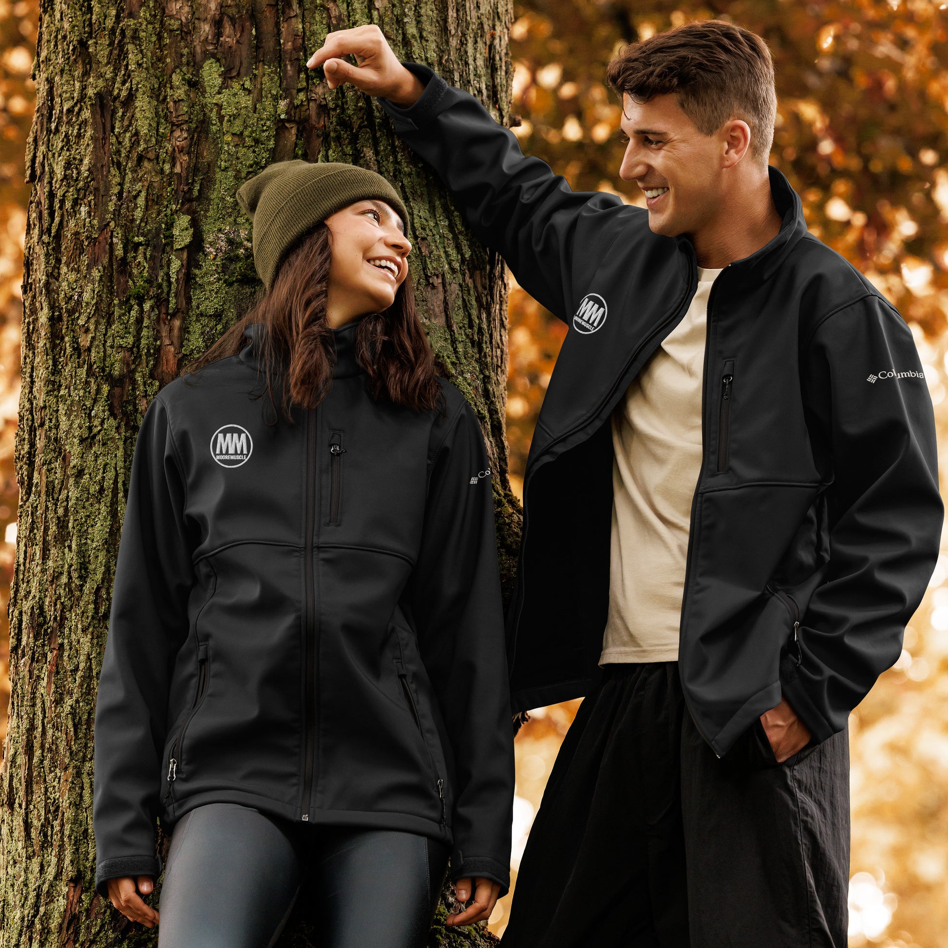 Man and woman wearing black MooreMuscle soft shell jackets outdoors during fall, showcasing everyday lifestyle wear.