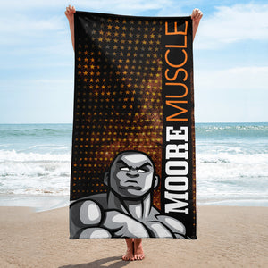 MooreMuscle stars beach towel held up on sand at the ocean shoreline with black and orange star pattern and bold character graphic facing forward